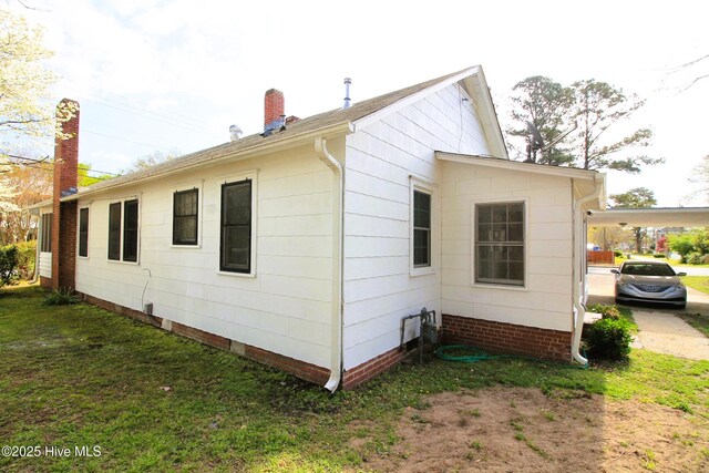 view of side of home with a chimney and a yard