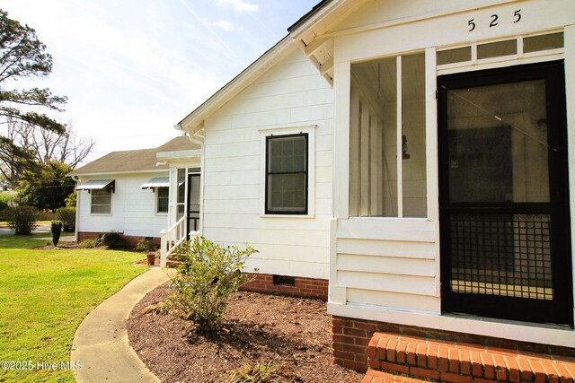 doorway to property featuring crawl space and a lawn