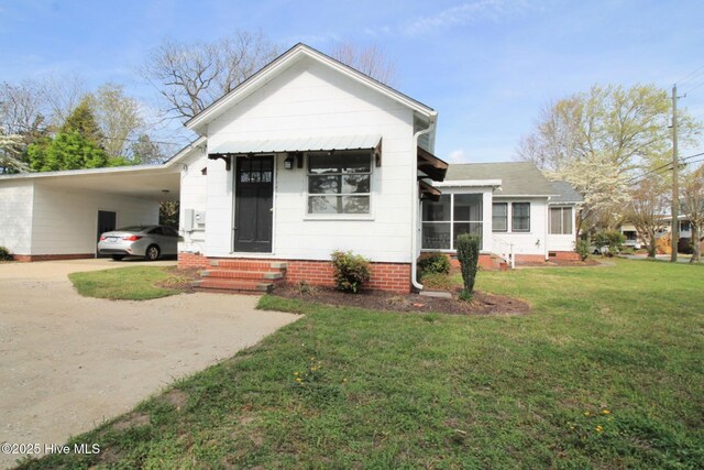 view of front of house featuring a front lawn, concrete driveway, entry steps, and a carport