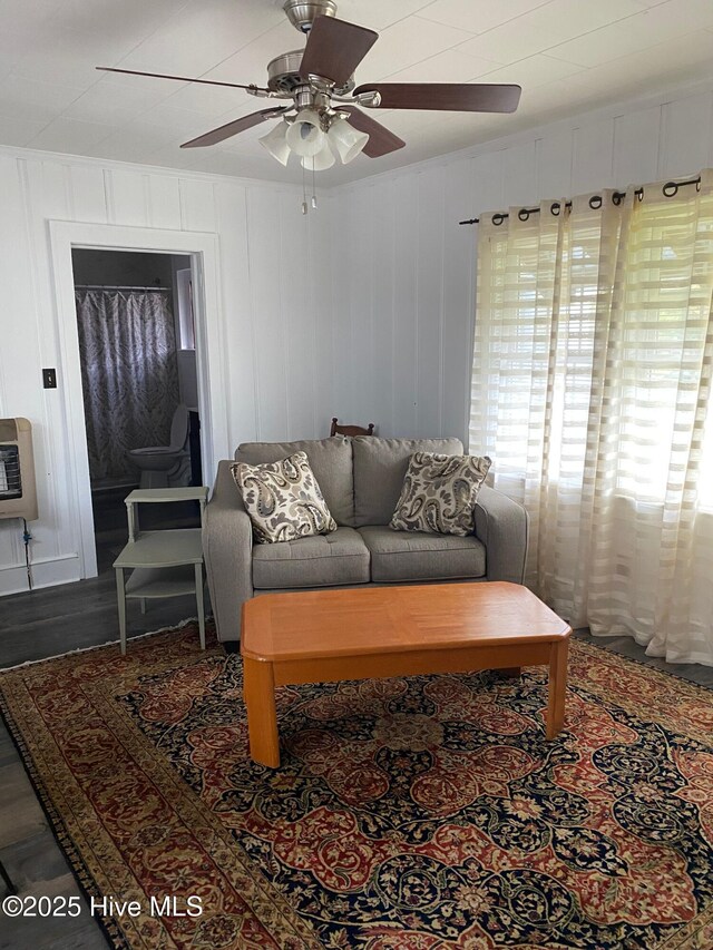 living room with heating unit, wood finished floors, a ceiling fan, and crown molding
