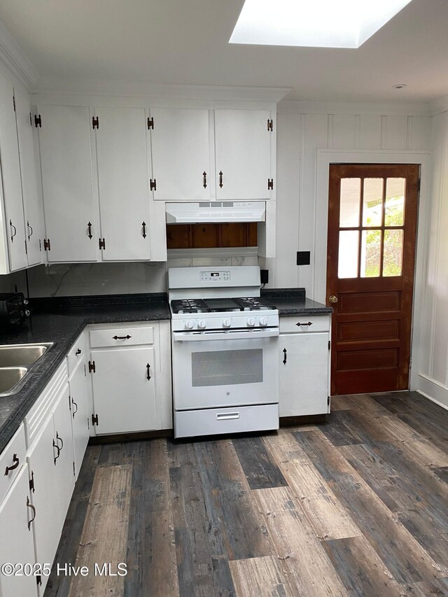 kitchen with dark countertops, white gas stove, and under cabinet range hood
