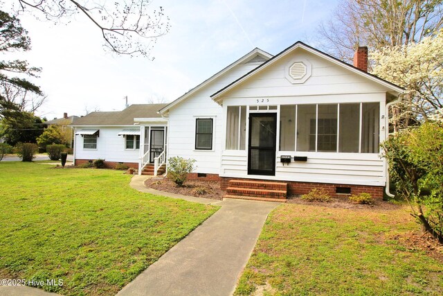 view of front of home with a sunroom, entry steps, a chimney, crawl space, and a front lawn