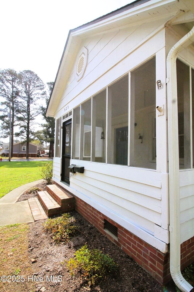 view of home's exterior with a sunroom and a yard