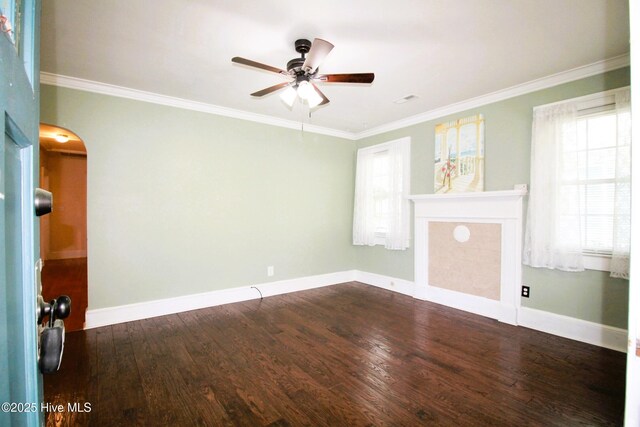 empty room featuring a ceiling fan, arched walkways, baseboards, and wood finished floors