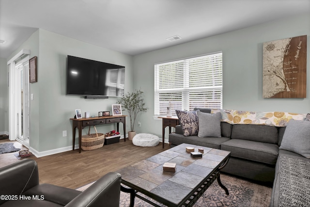 living area featuring baseboards, visible vents, and wood finished floors
