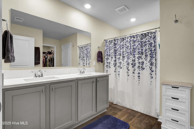 full bath with wood finished floors, a sink, double vanity, and visible vents