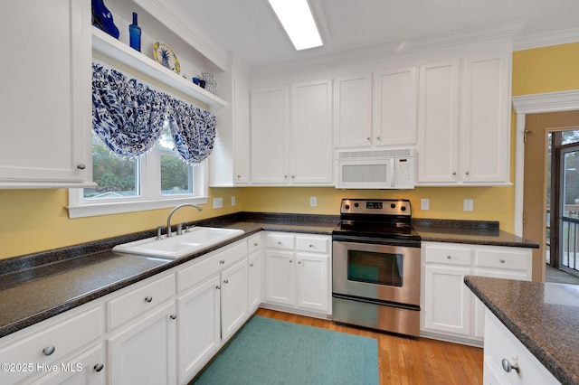 kitchen featuring white cabinetry, a sink, white microwave, and stainless steel electric range