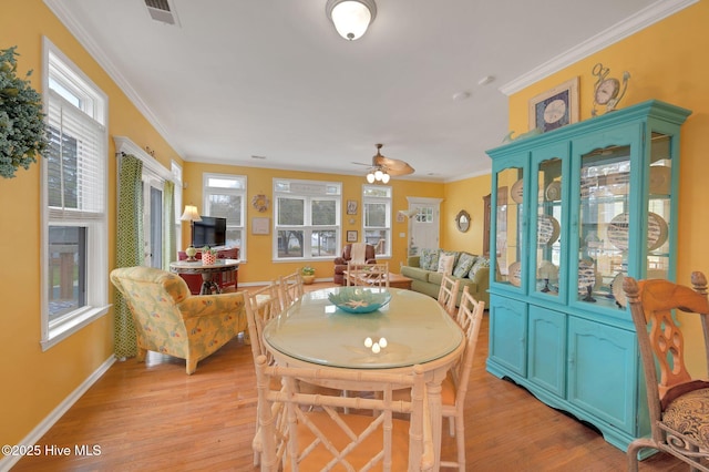 dining area with light wood-type flooring, crown molding, a healthy amount of sunlight, and visible vents