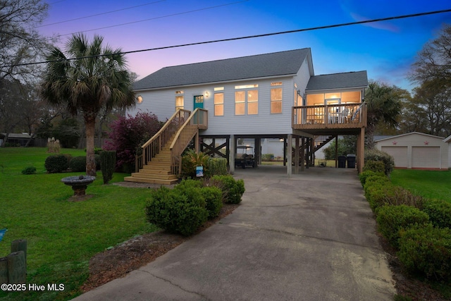 coastal inspired home with driveway, stairway, roof with shingles, a lawn, and a carport