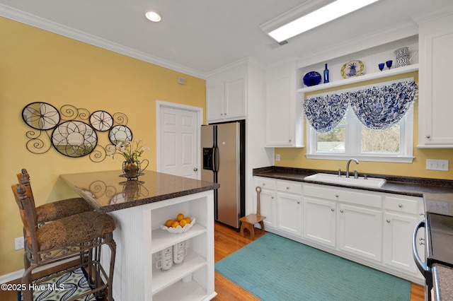 kitchen featuring a sink, stove, stainless steel fridge, and open shelves