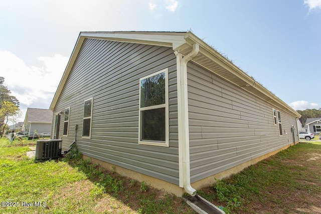 view of side of property with central AC unit and a yard