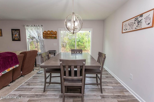 dining area featuring baseboards, an inviting chandelier, and wood finished floors