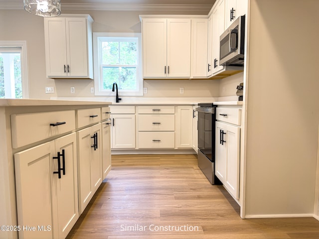 179 N Brightleaf Dr, Minnesott Beach, NC 28510 - kitchen featuring stainless steel appliances, ornamental molding, light countertops, light wood-style floors, and white cabinetry
