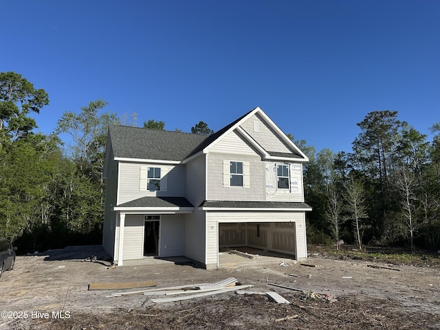 view of front facade with a shingled roof and a garage