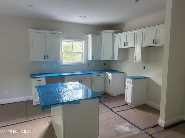 610 Poppleton Dr, Hampstead, NC 28443 - kitchen with a kitchen island, visible vents, baseboards, and white cabinets