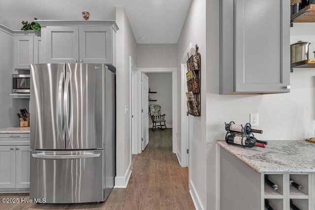 1560 White Oak River Rd, Maysville, NC 28555 - kitchen with appliances with stainless steel finishes, open shelves, wood finished floors, baseboards, and light stone counters