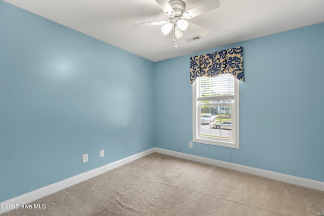 spare room featuring carpet floors, visible vents, baseboards, and ceiling fan