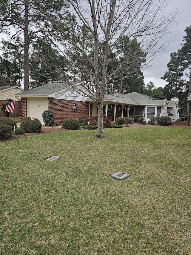 view of front of house with an attached garage, brick siding, and a front yard