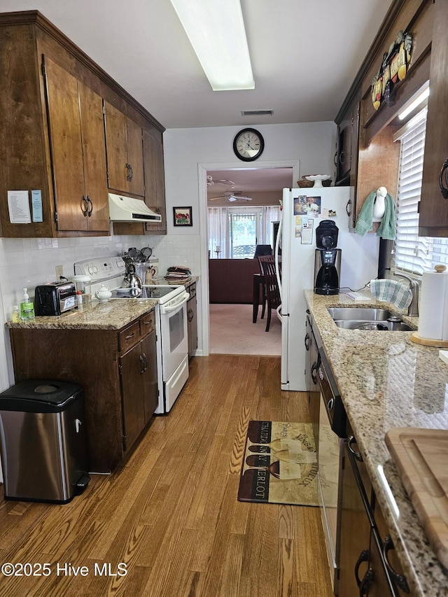 kitchen with exhaust hood, dark brown cabinetry, light wood-type flooring, visible vents, and white electric range
