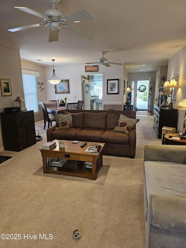 living room with a ceiling fan, light carpet, and plenty of natural light