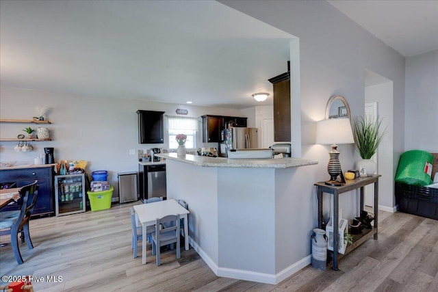 115 Kenmore Ct, New Bern, NC 28560 - kitchen featuring light wood finished floors, freestanding refrigerator, light countertops, beverage cooler, and a breakfast bar area