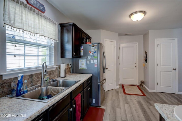 115 Kenmore Ct, New Bern, NC 28560 - kitchen featuring dark brown cabinets, a sink, light wood-style floors, light countertops, and freestanding refrigerator