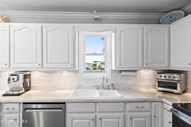 kitchen featuring stainless steel dishwasher, white cabinets, light countertops, a sink, and backsplash