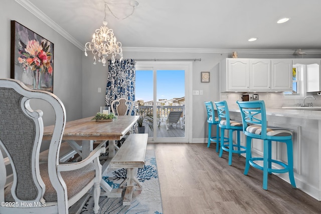 dining area with a chandelier, plenty of natural light, light wood-style flooring, and ornamental molding