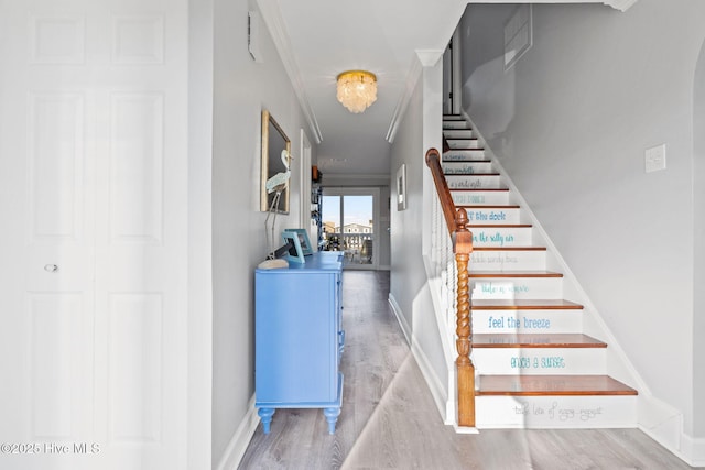 stairway with wood finished floors, baseboards, and ornamental molding