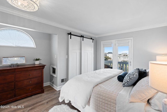 bedroom featuring visible vents, a barn door, access to exterior, wood finished floors, and multiple windows