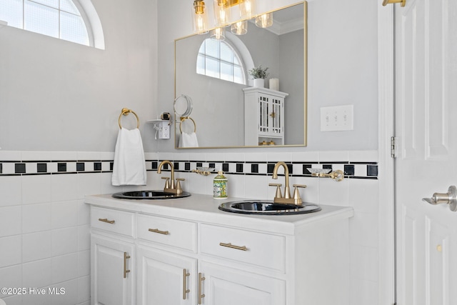 bathroom featuring double vanity, a sink, wainscoting, and tile walls