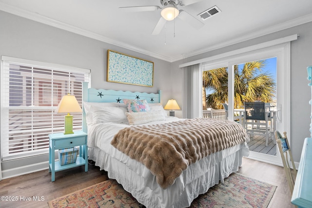 bedroom with visible vents, multiple windows, crown molding, wood finished floors, and access to outside