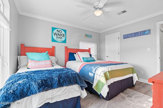 bedroom with visible vents, baseboards, ornamental molding, and wood finished floors
