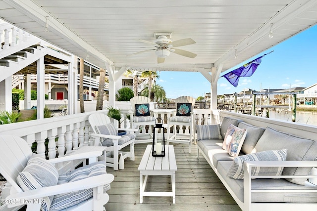 deck with a water view, an outdoor living space, and a ceiling fan