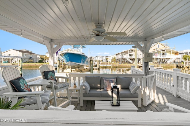 wooden terrace with a water view, a boat dock, a ceiling fan, and a residential view