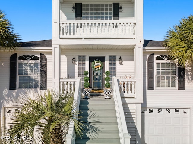 property entrance with an attached garage, a shingled roof, covered porch, and a balcony