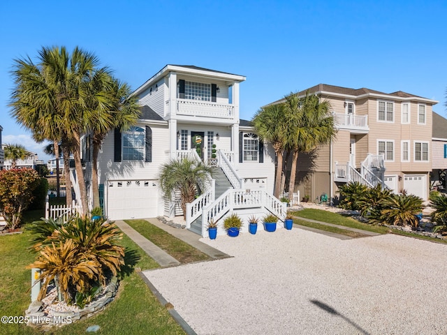 coastal home with an attached garage, a balcony, driveway, and stairs