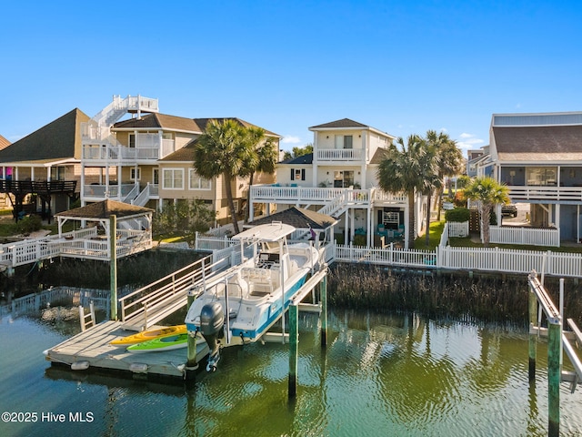 dock area featuring a water view, fence, and boat lift