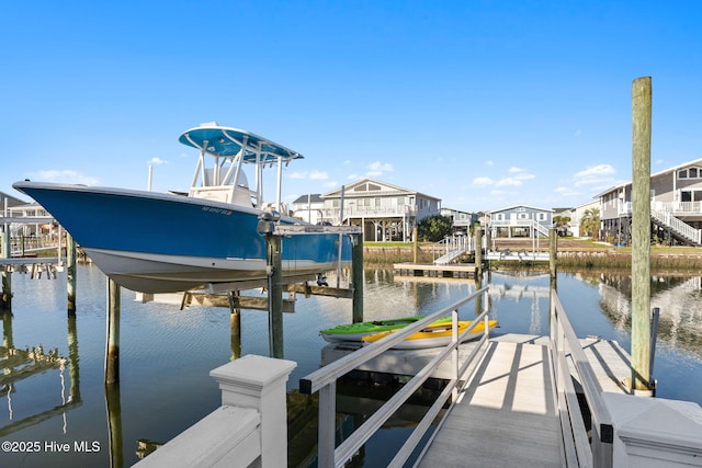 view of dock featuring a water view, a residential view, and boat lift