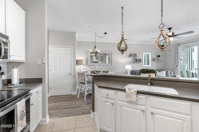 1135 Park Rd SW Unit 1203, Sunset Beach, NC 28468 - kitchen with a sink, dark countertops, light tile patterned flooring, white cabinets, and a textured ceiling