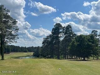 surrounding community with a water view, a lawn, and golf course view