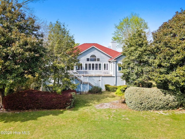 178 Edgewater Cir, Sunset Beach, NC 28468 - rear view of house with a chimney, a lawn, and stairs