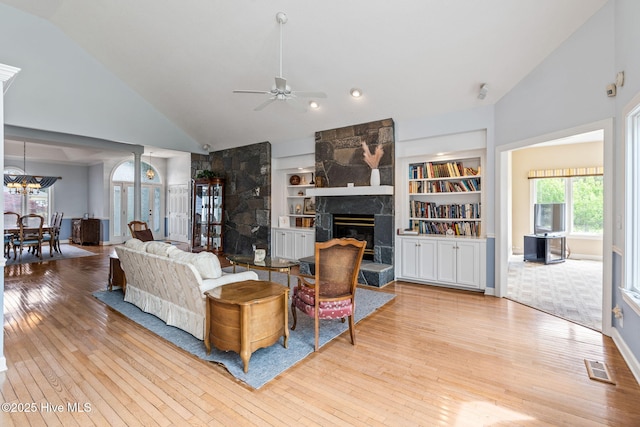 178 Edgewater Cir, Sunset Beach, NC 28468 - living room featuring visible vents, built in features, a stone fireplace, ceiling fan, and hardwood / wood-style floors