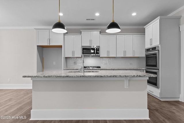 804 Winds Way, Aberdeen, NC 28315 - kitchen with appliances with stainless steel finishes, tasteful backsplash, a center island with sink, light stone counters, and decorative light fixtures