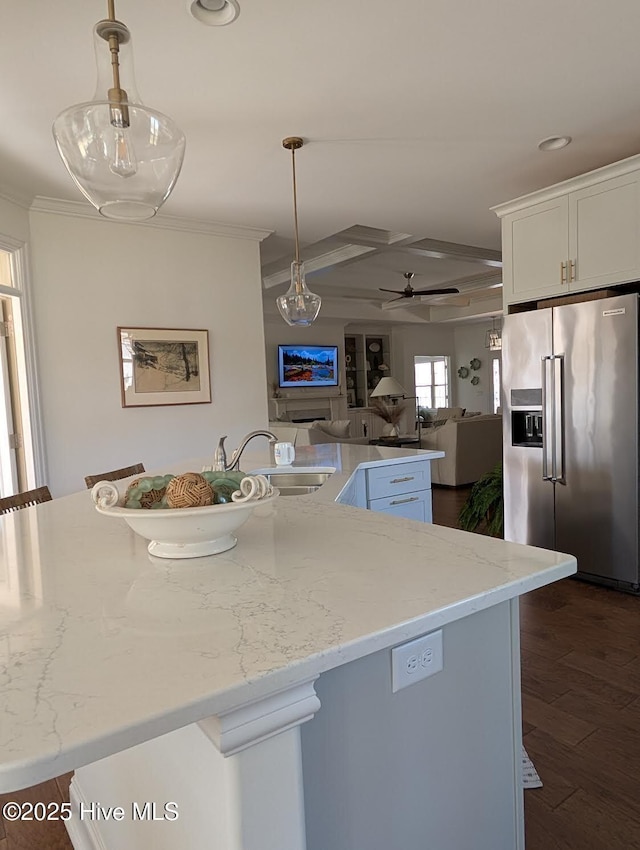 kitchen with a sink, open floor plan, high end fridge, crown molding, and dark wood-type flooring