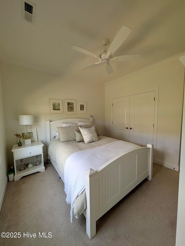bedroom with light carpet, visible vents, a ceiling fan, a closet, and crown molding