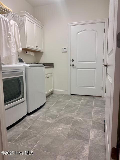 laundry area with cabinet space, baseboards, and washer and clothes dryer