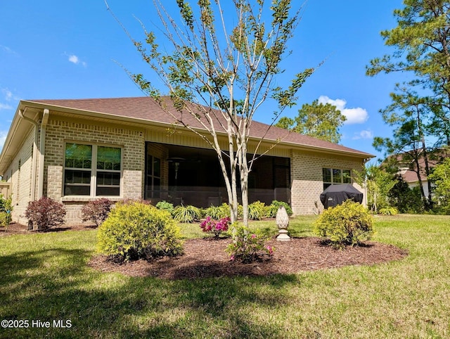 view of front of property featuring brick siding, a shingled roof, and a front yard