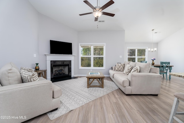 330 Independence Blvd, Newport, NC 28570 - living room with visible vents, ceiling fan with notable chandelier, a fireplace with flush hearth, vaulted ceiling, and wood finished floors