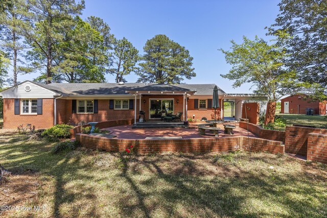 rear view of property with a patio area, a lawn, and brick siding